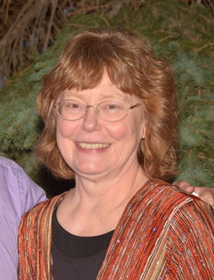 smiling woman with reddish hair and glasses wearing red jacket over black shirt