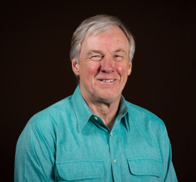 portrait of smiling gray-haired man wearing turquoise button down shirt