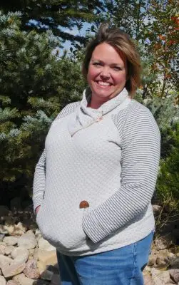 A white woman with short blonde hair wearing a white long sleeve.
