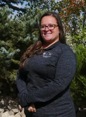 A white woman with long brown hair and glasses wearing a black long sleeve.