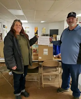 smiling middle-aged man and woman each hold the corner of a certificate of completion showing they finished their electric pressure cooker course.
