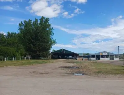 Several agricultural buildings and trees in a rural setting.
