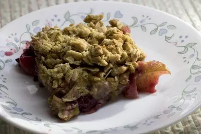 A square piece of dessert topped with granola on a small plate.