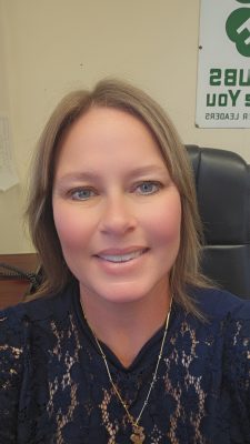 A white woman with blue eyes and shoulder length blonde hair. Her face is very smooth.