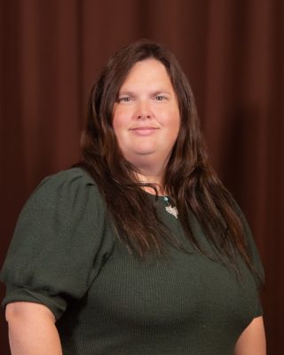 A heavier woman with white skin and long wavy brown hair. 