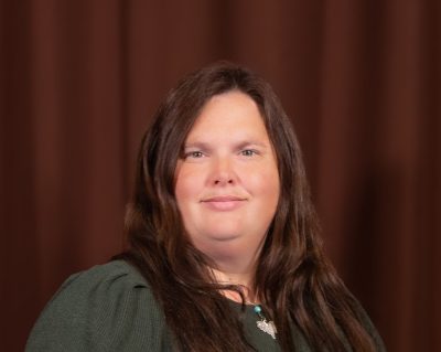 A heavier woman with white skin and long wavy brown hair.