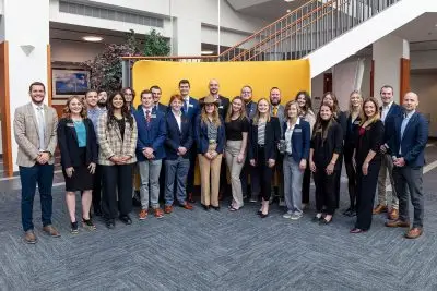 A group shot of about 20 young adults in formal clothing.