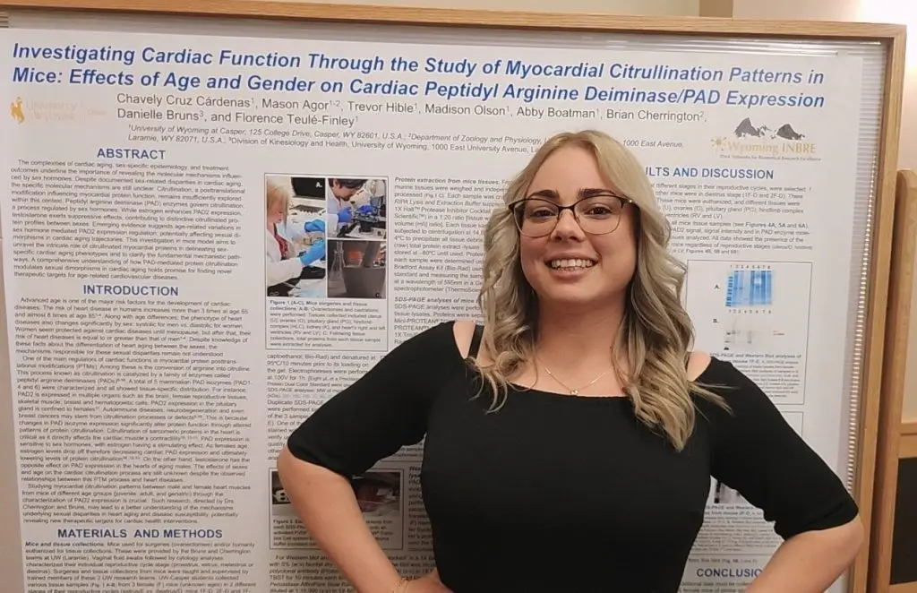 smiling woman stands in front of a scientific poster