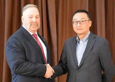 Two men wearing formal clothing shake hands