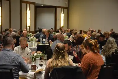 A crowd of people in formal clothing at tables.