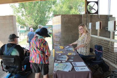 A woman showing several flyers and papers to two people.