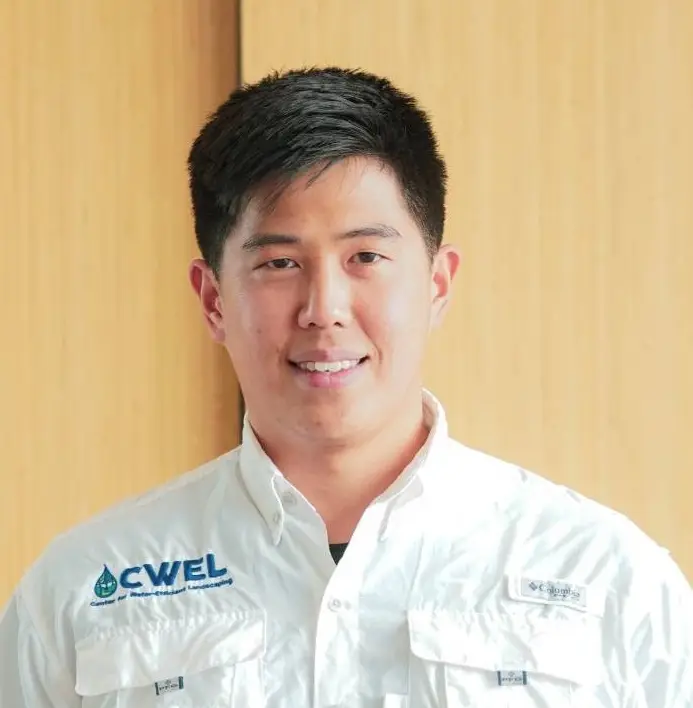 headshot of smiling man wearing white shirt with pockets