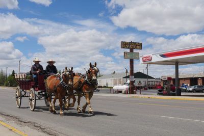 Pistol and Pete pull a carriage through the outskirts of Laramie, by a gas station.