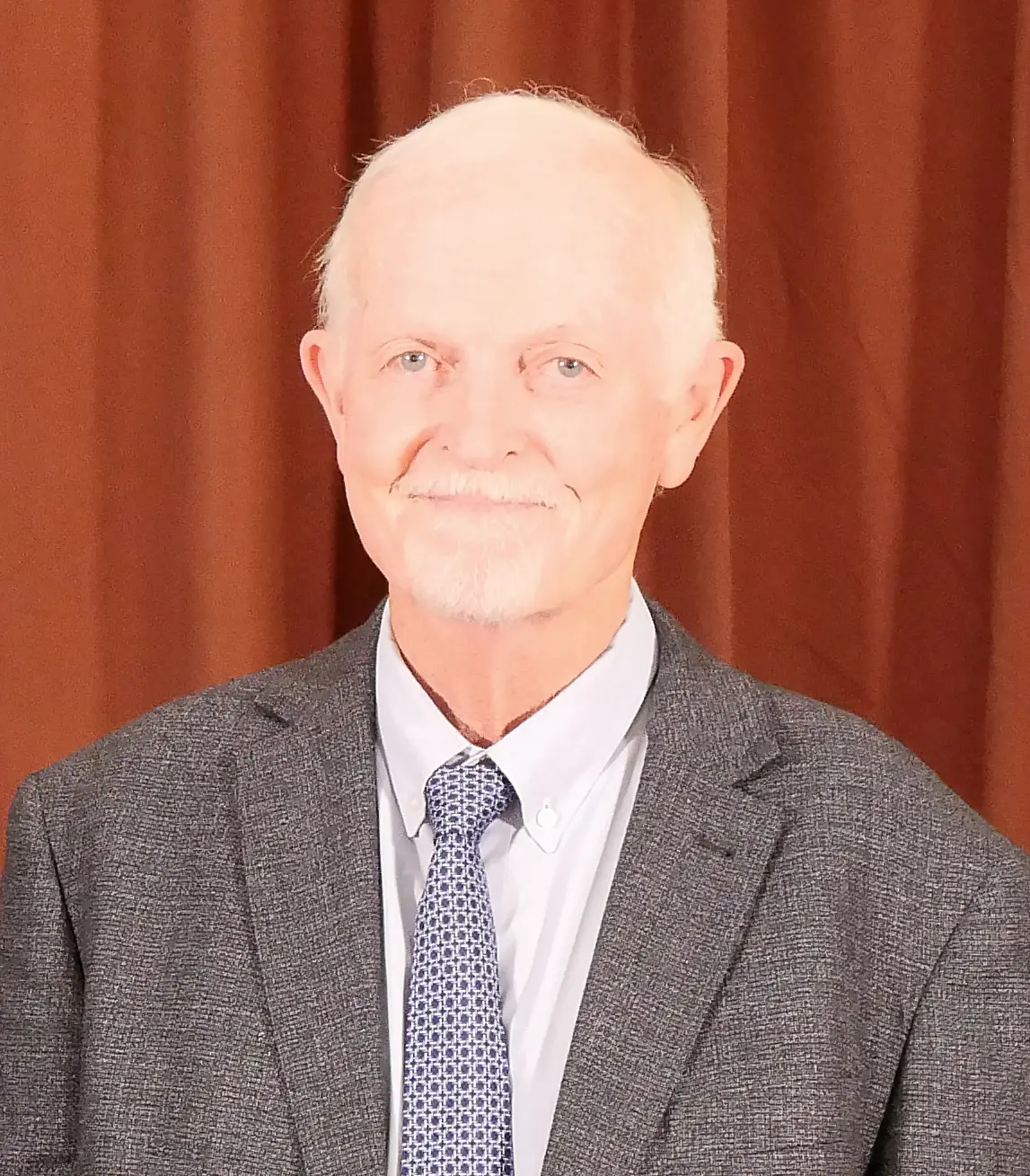 smiling man wearing suit jacket, collared shirt, and tie