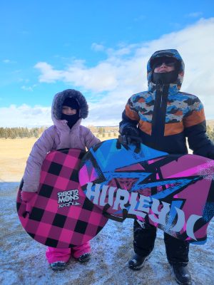 Two kids holding sleds.
