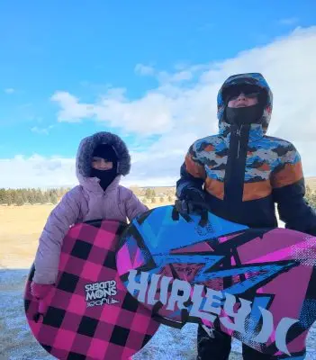 Two kids holding sleds.