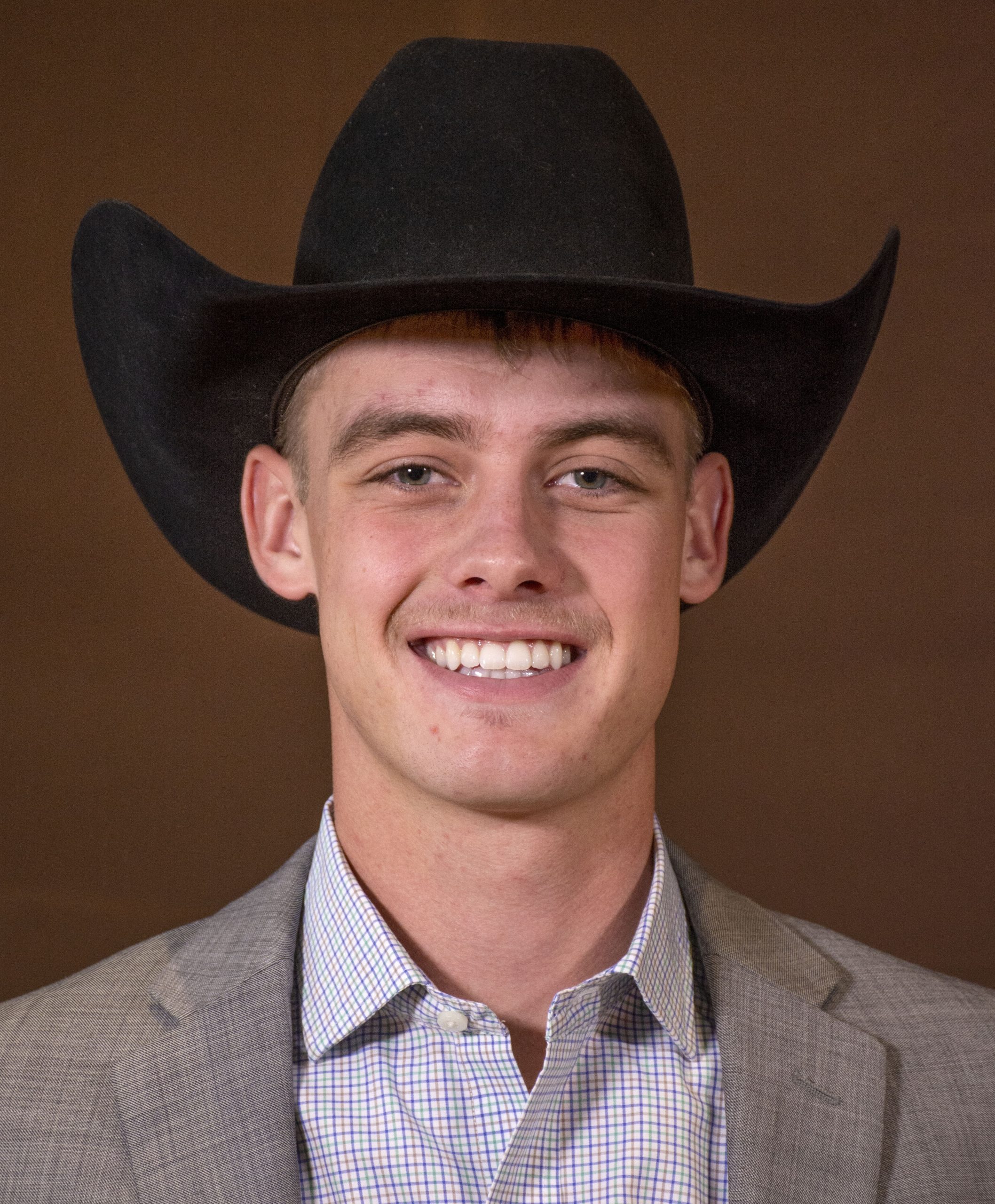 headshot of a smiling man in formal attire and a cowboy hat