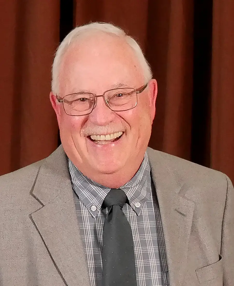 smiling man wearing suit jacket, collared shirt, and tie