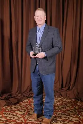 A man in formal clothing holding a glass plaque.
