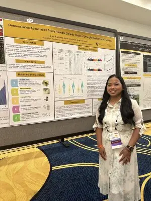 A young woman stands by a scientific poster.