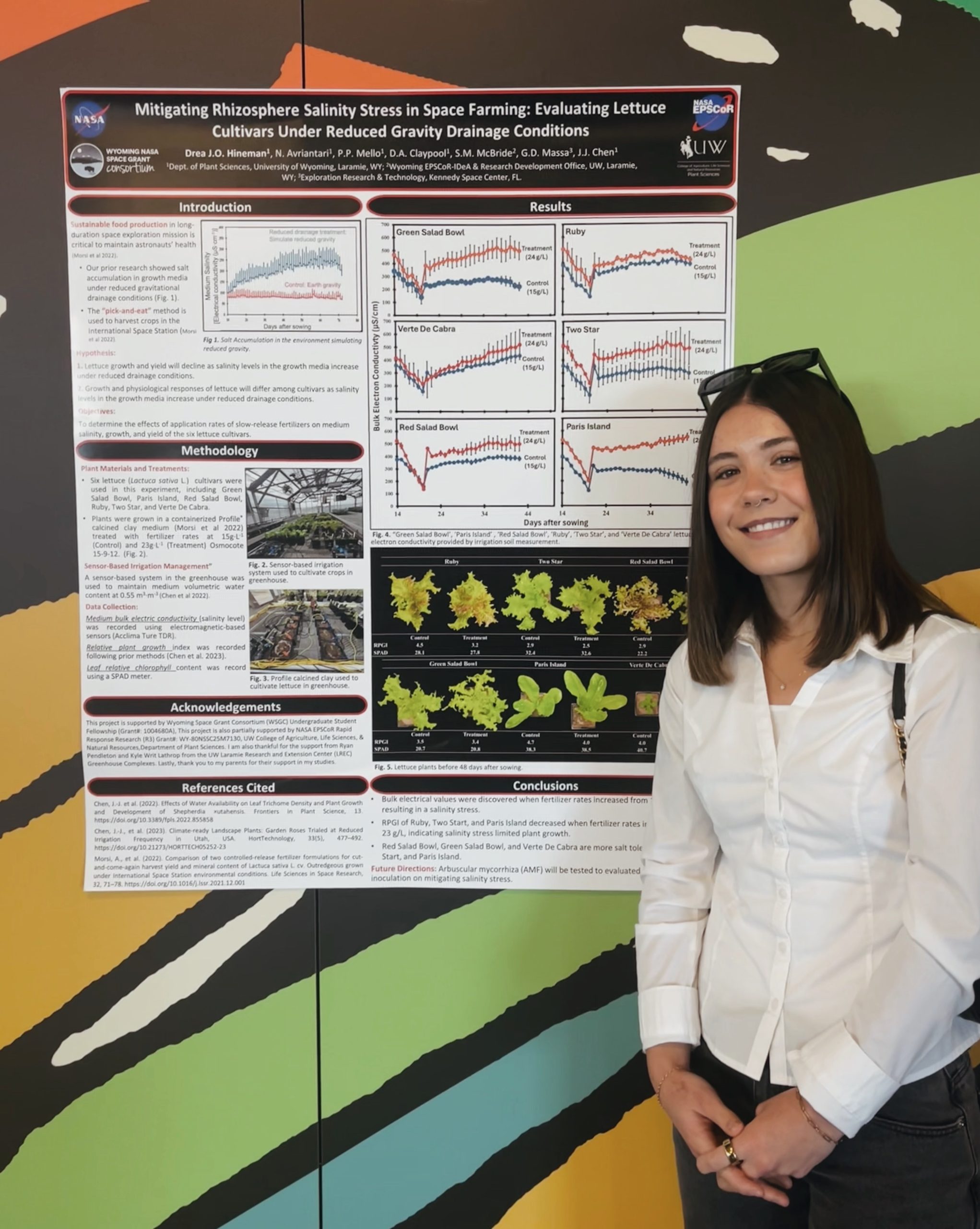 Drea Hineman stands beside her research poster, titled "Mitigate Rhizosphere Salinity Stress in Space Farming: Evaluating Lettuce Cultivars Under Reduced Gravity Drainage Conditions," at the 2025 Spacepoint poster session.