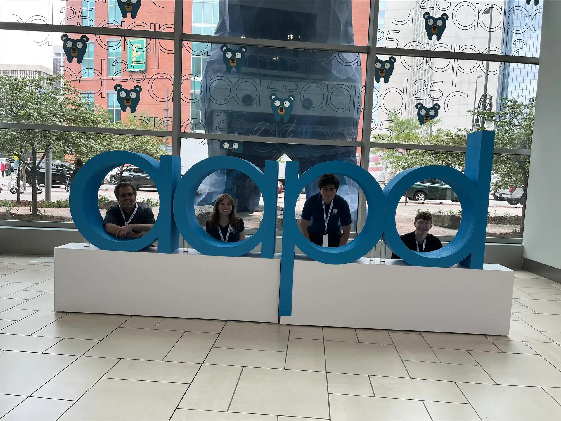 Four people pose with a large statue of the letters "aapd."