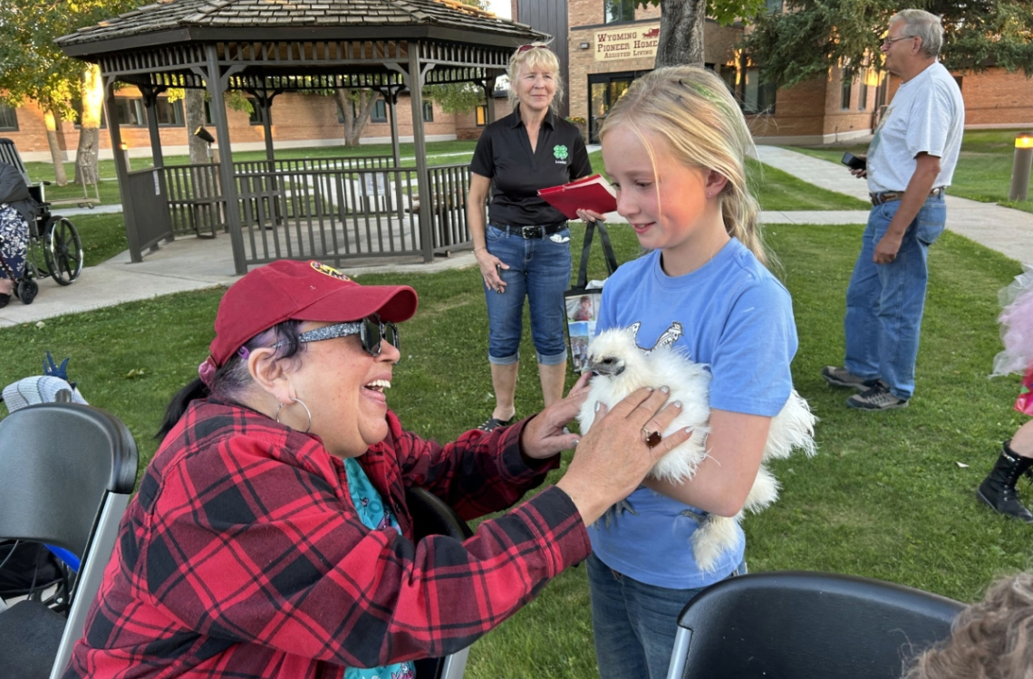 A member of the Cowpokes 4-H club shows a Pioneer Senior Center resident a chicken. Photo courtesy of Hannah Welfl-Postma.