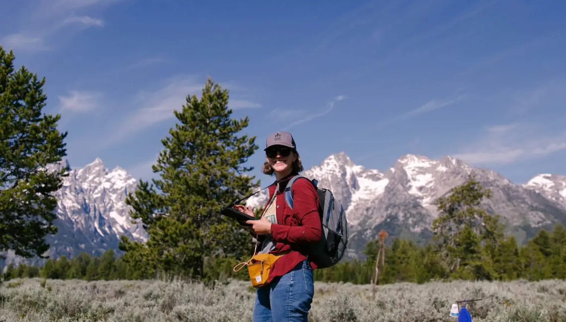 Amy Storey stands in sagebrush steppe with mountains in the background.