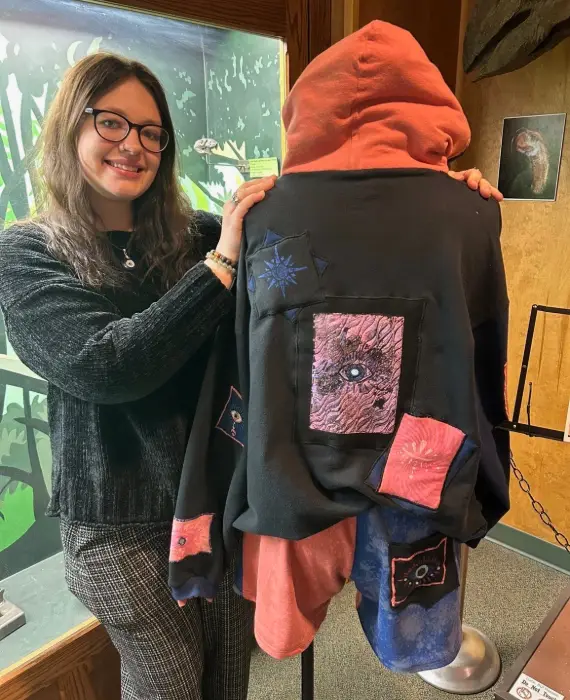 Izzy Nichols with an original creation. This set was upcycled from thrifted materials and features a variety of fiber art techniques. Some of those techniques include surface dying, gelli printing, embroidery, and more. Photo by Greta Quill.