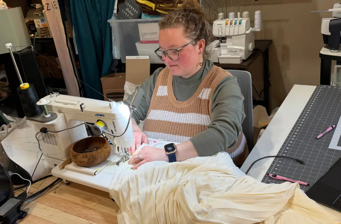 UW alumna Lauren Carlson, of Casper, Wyo., alters a wedding dress. She owns and operates Joyful Juniper Alterations, specializing in alterations of women’s bridal and formal wear. Photo by Caleb Carlson.