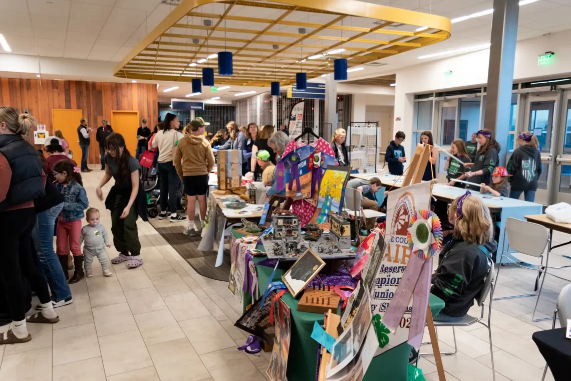 4-H youth display projects and engage visitors at booths during a busy indoor community event.