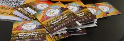 Small booklets labeled "2025 Event Passport: Albany County."