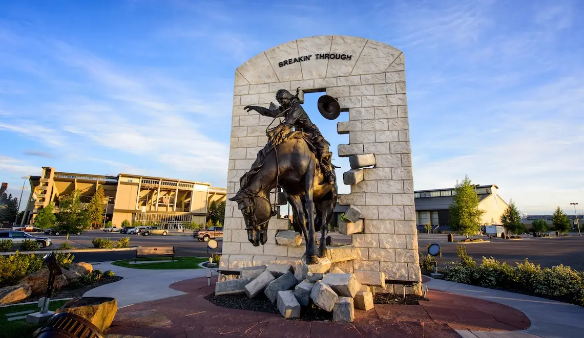 Bronze statue of a female horse rider breaking through a wall titled "Breakin' Through"