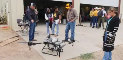 Several people look at a parked agricultural drone.