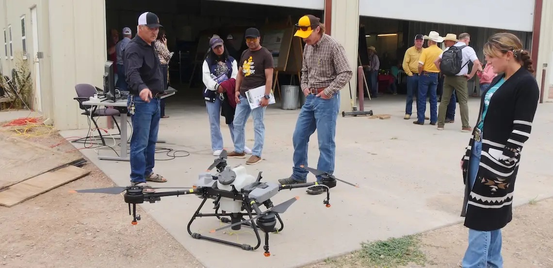Several people look at a parked agricultural drone.