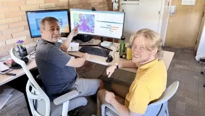 Albeke and Kirkpatrick sit in front of computer displaying a graph and a chart.