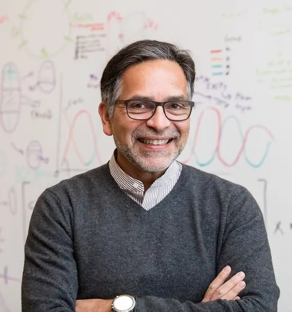 Alejandro Sánchez Alvarado stands in front of a whiteboard.