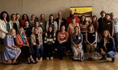 large group of people organized into two rows pose together next to a sign advertising UW's Department of Family and Consumer Sciences