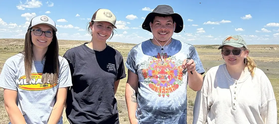 Four people stand in a field; Jahshua Sanchez is holding a bird.