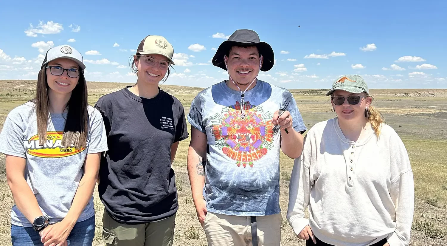 Four people stand in a field; Jahshua Sanchez is holding a bird.