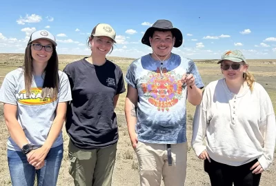 Four people stand in a field; Jahshua Sanchez is holding a bird.