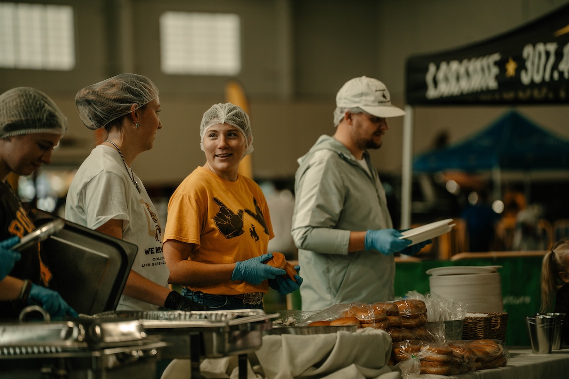 Four students talk as they serve food.
