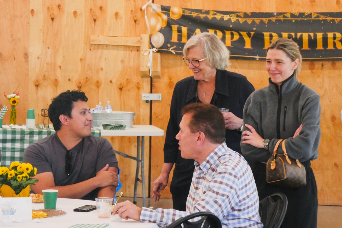 Mary Martin visits with guests seated around a table during her retirement celebration.