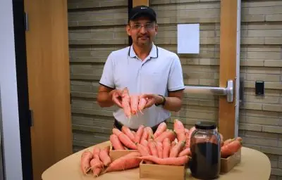 Resham Thapa with dozens of carrots which are about 6-8 inches long and 1-2 inches thick